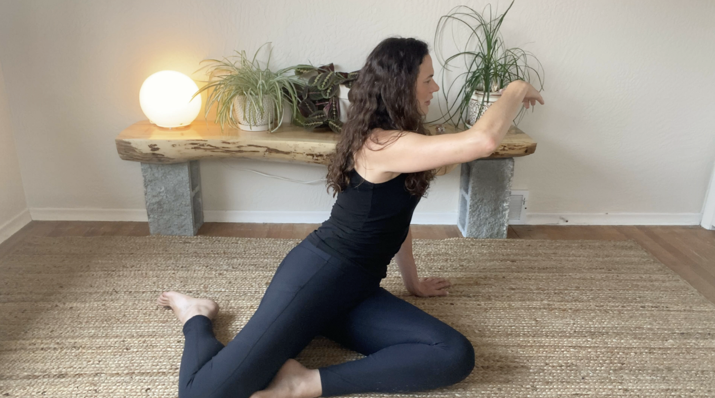 Someone moving through a grounded stretch at home, present in her body